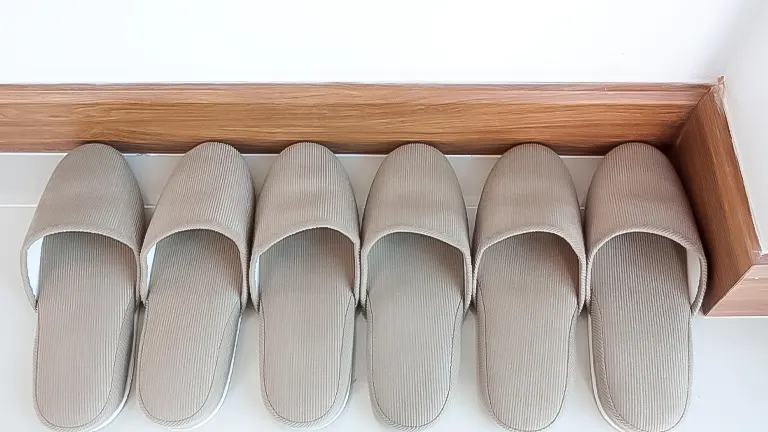 Neatly arranged beige slippers on wooden shelf