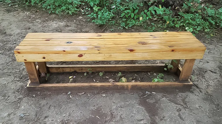 Bench consists of smooth, polished wooden planks for the seat, supported by rough, unpolished logs