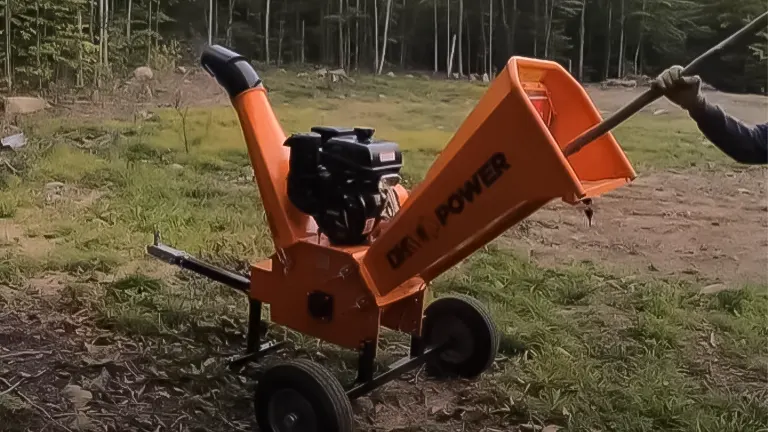 Side view of an orange DK2 Power gas wood chipper with a visible engine and exhaust, in an outdoor setting with trees