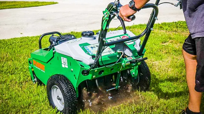 person operating a green lawn aerator on a grassy field. Only the lower body of the operator is visible