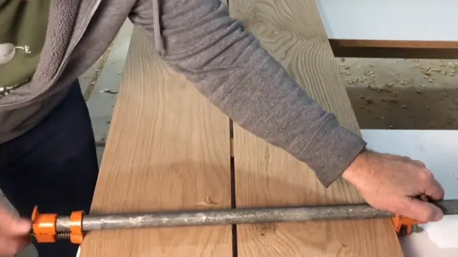 Person using a clamp to hold wooden planks together