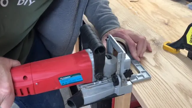 Person using a red and silver biscuit joiner on wood