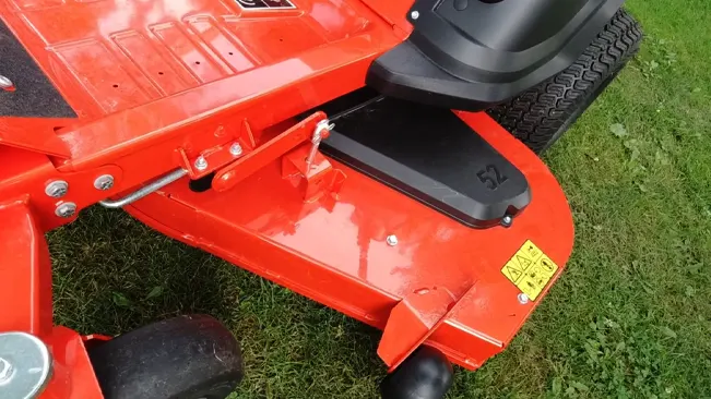 Close-up of a red lawnmower’s body and wheels on grass