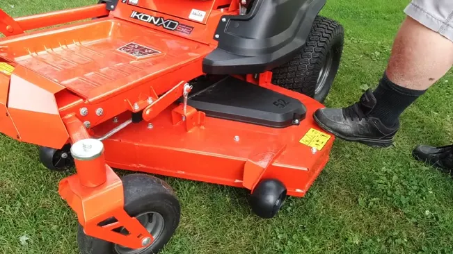 Person standing next to a red IKON XD lawnmower on grass.