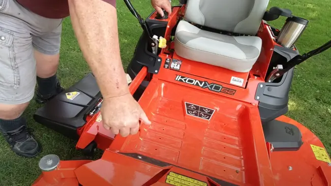 Person operating a red IKON XD 52 lawnmower on a grassy field.