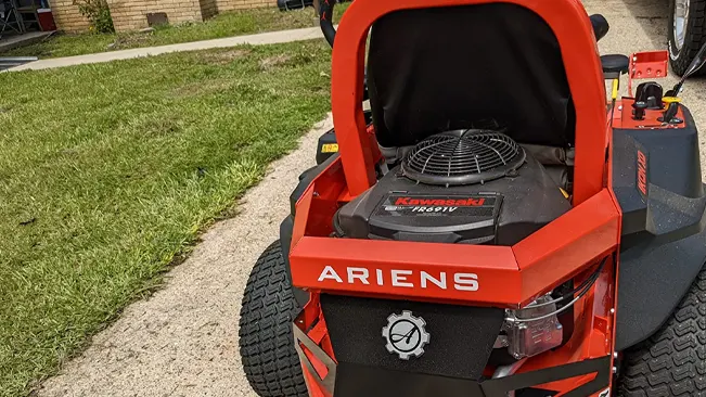 Ariens lawnmower with a Kawasaki engine, parked on freshly cut grass next to a concrete path.