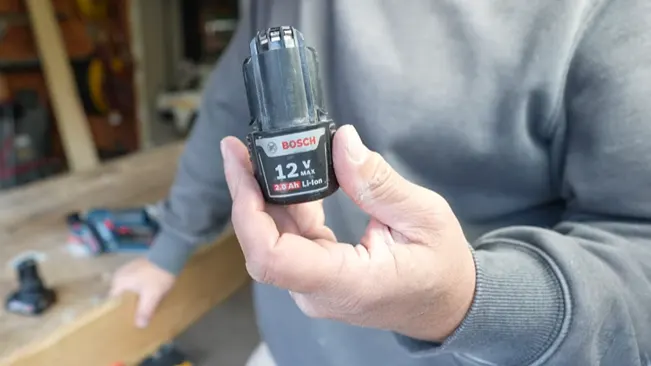 Person displaying Bosch 12V max battery in workshop