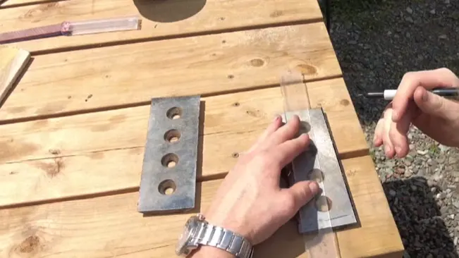 Person marking measurements on a wooden plank outdoors