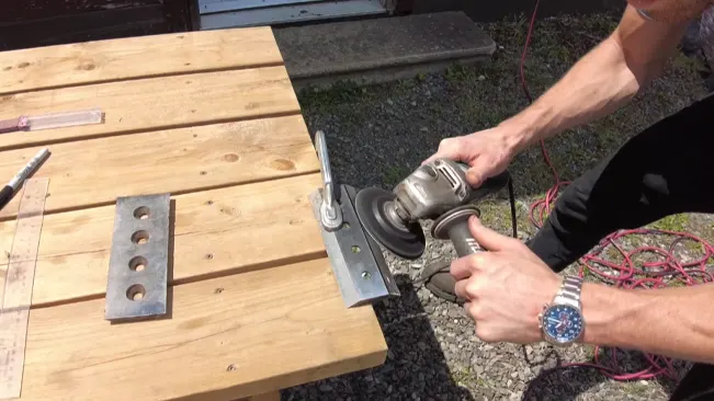 Person using a grinder on a wooden surface outdoors