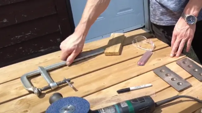 Hands near tools and materials on a wooden surface, indicating a project or repair