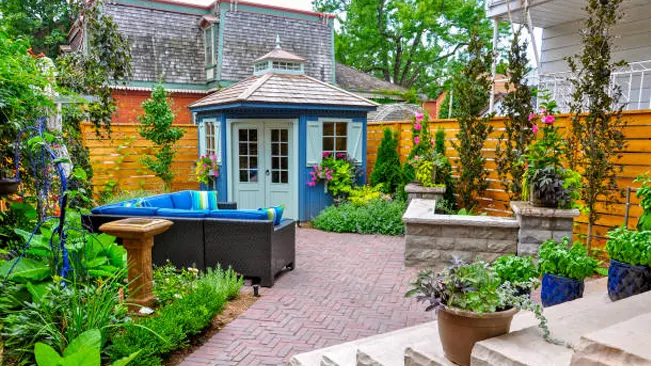 Charming garden shed with blue doors in a vibrant suburban backyard oasis.