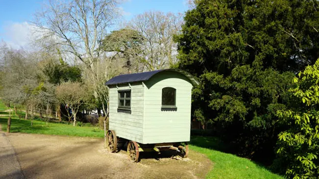 Vintage shepherd's hut on wheels in a pastoral setting.