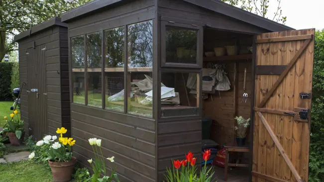 Modern garden shed with large windows and open door, showcasing a panoramic view.