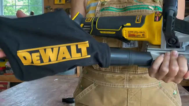 Person holding a DEWALT power tool and cloth, wearing a tool belt