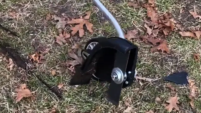 Leaf scooper tool on a grassy ground covered with fallen leaves