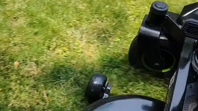 Close-up of a lawnmower in action on grass.