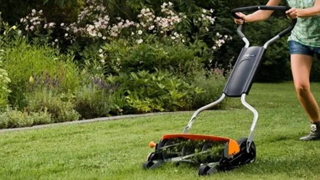 Person mowing a lush green lawn with a push mower