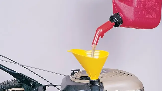 Gas can pouring into lawn mower funnel