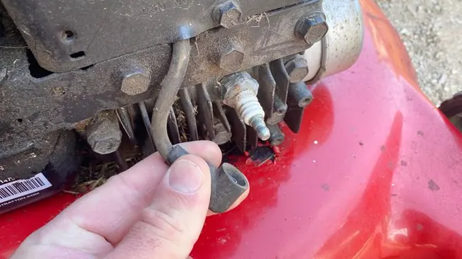 Hand holding a hose from Spark plug