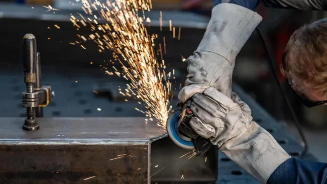 Person using a grinding tool on metal, creating sparks.