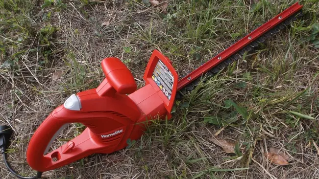 Red electric hedge trimmer on grass