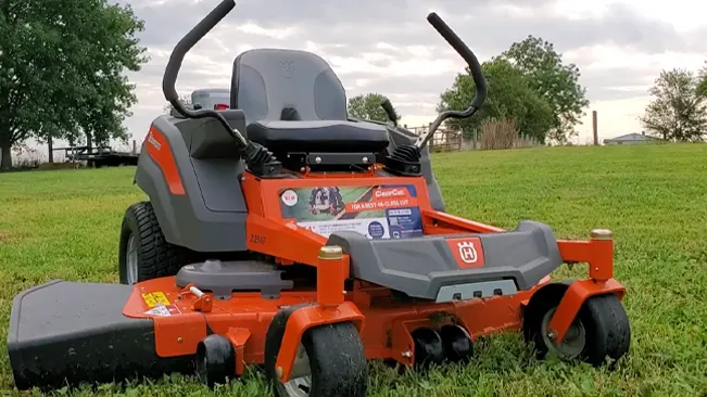 The mower has large, sturdy wheels and a black cushioned seat