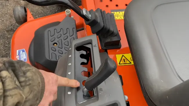 person’s hand interacting with the controls riding lawn mower