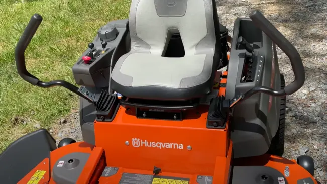 bright orange Husqvarna riding lawnmower on a grassy area with various controls around the seating area