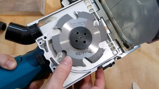 Person holding a circular saw, displaying its blade and internal components