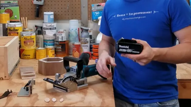 Person in a workshop holding a Makita power tool battery