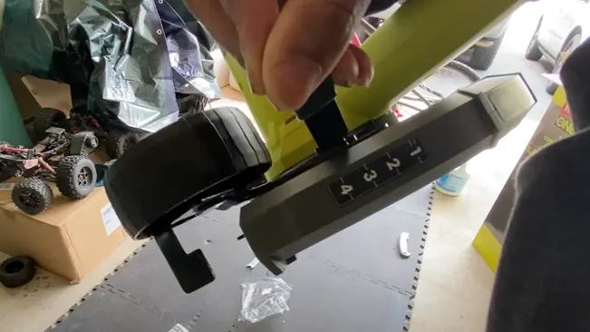 Person assembling a yellow and black Adjusting ‘RYOBI’ in a cluttered workspace