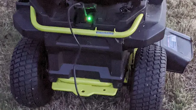 Rear view of a lawnmower with a green light indicator on a grassy field