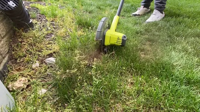 using a yellow Lawn Edger to maintain overgrown green grass.