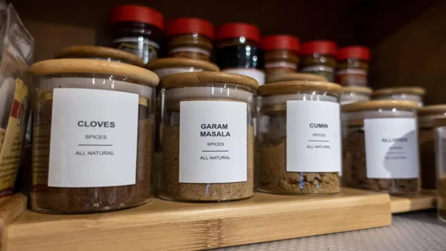 A close-up of a spice rack with four glass jars filled with colorful spices