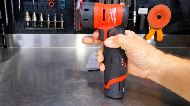 hand holding a red and black cordless sander