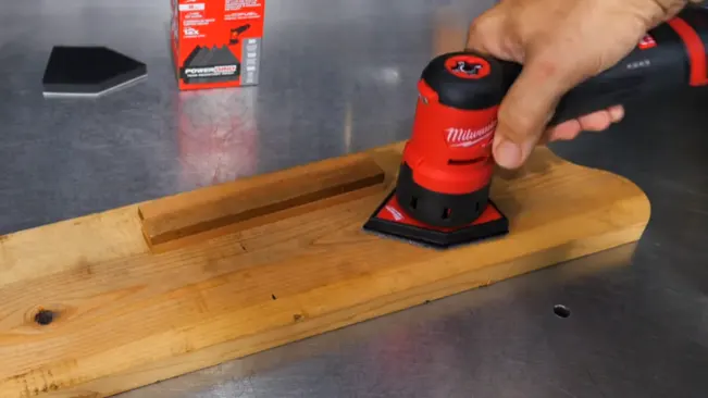 person skillfully using a Milwaukee sander on a wooden board