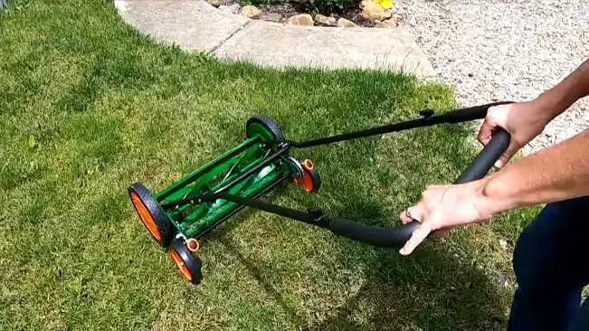 Person manually mowing a green lawn