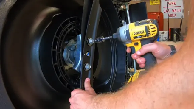 Person Tighten a lawn mower blade using cordless drill