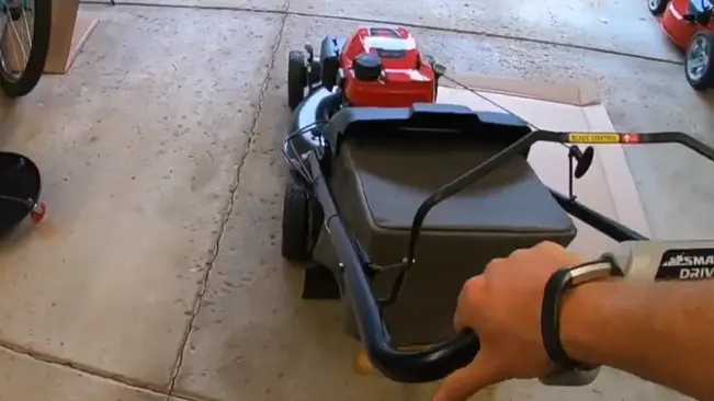Person’s hand pushing a lawnmower in a garage