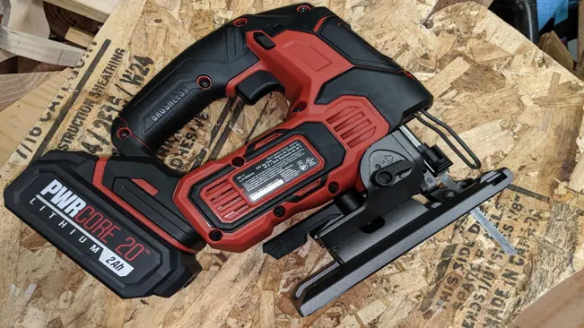 Red and black jigsaw power tool on a wooden surface