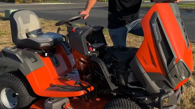 person showcasing an open orange and black riding lawnmower