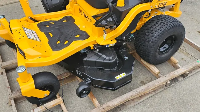 bright yellow riding lawnmower labeled “ULTIMA 50” positioned on a wooden pallet.