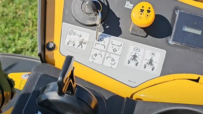 Control panel of a yellow machinery with safety instructions and a set of keys in the ignition