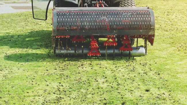 mechanical lawn aerator in action on a well-maintained green field.