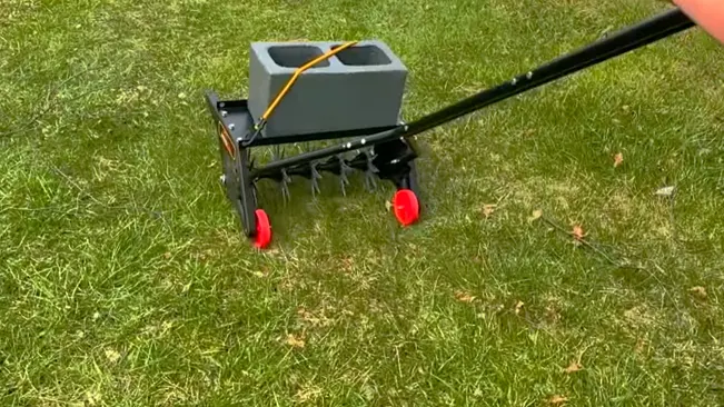 Person using a lawn aerator on green grass.