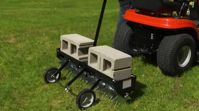 Lawn mower pulling a small trailer with cinder blocks.