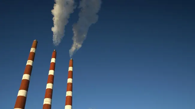 Industrial chimneys emitting smoke into a clear blue sky