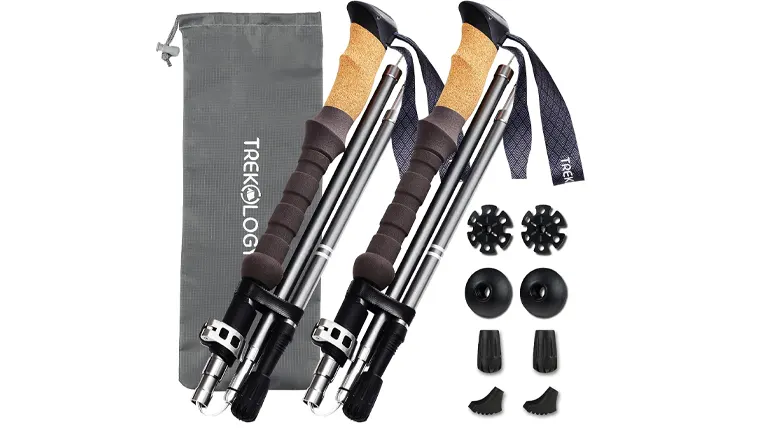 Graphite-colored TREKOLOGY trekking poles with cork handles and adjustable straps, flanked by black and gray accessories including various tips and baskets, next to a gray storage pouch.