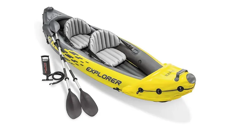 Yellow and gray inflatable kayak with two paddles and a high-output air pump, designed for two persons with adjustable seating and a prominent Explorer graphic on the side.