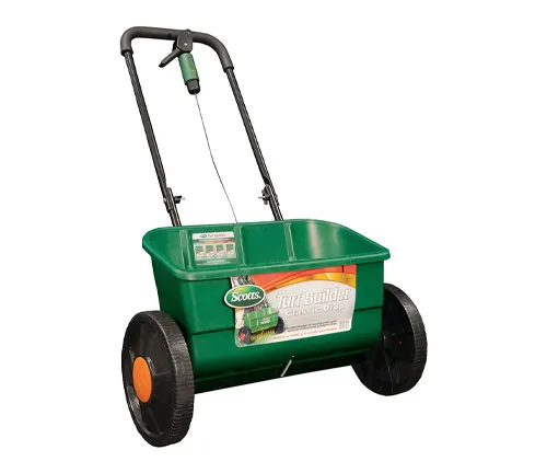 A green Scotts Turf Builder Classic Drop Spreader, a lawn care equipment for distributing fertilizer or seed evenly across grass.